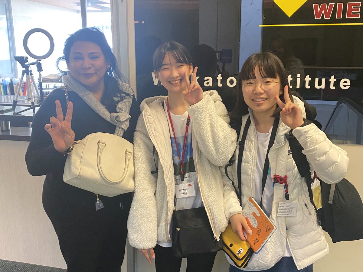 Three femalesâ€”an adult staff member/teacher and two young Asian international students wearing lanyards...