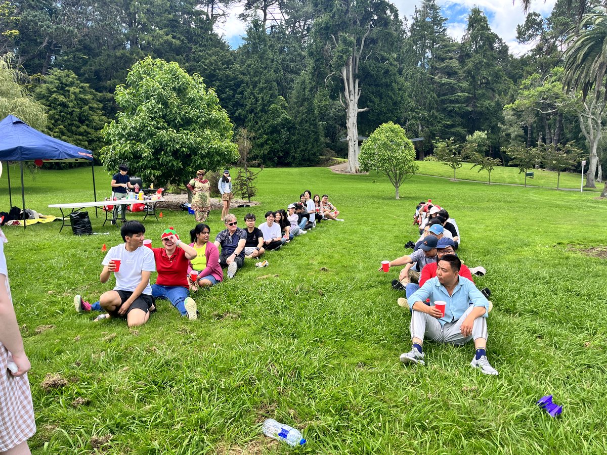 A large, diverse group of international students and staff participating in an outdoor social gathering...