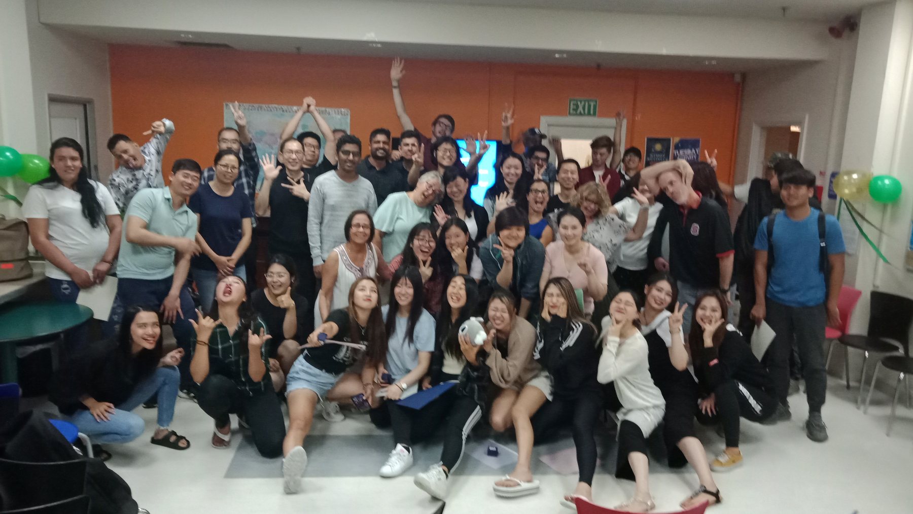 A vibrant, energetic large group photo of diverse international students and teachers posing playfully in...