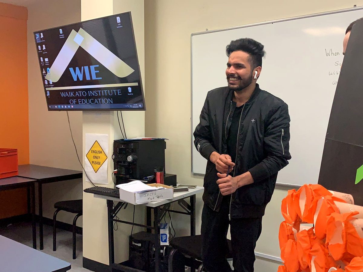 A smiling male student presenting during an interactive classroom activity at WIE