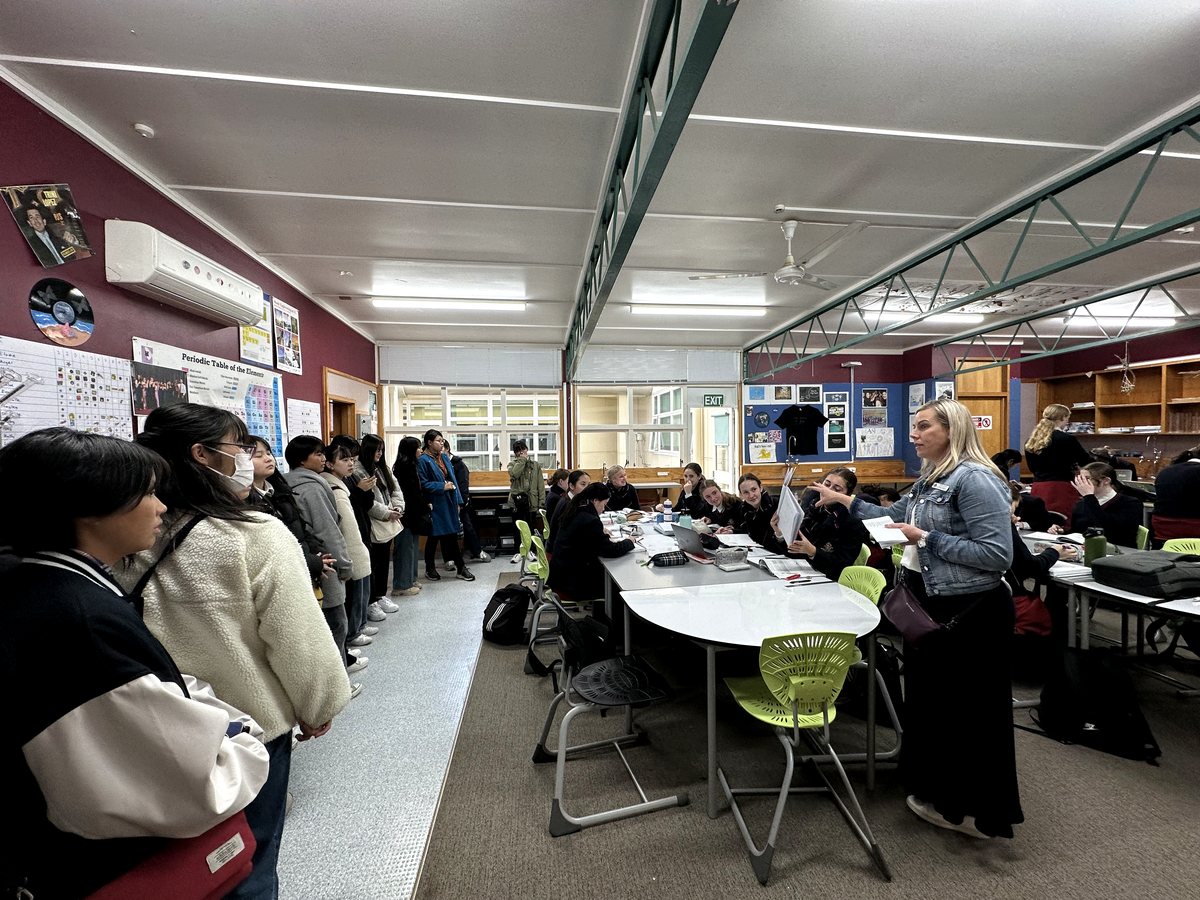 A wide-angle indoor classroom scene showing an interactive learning session with a female teacher guiding...