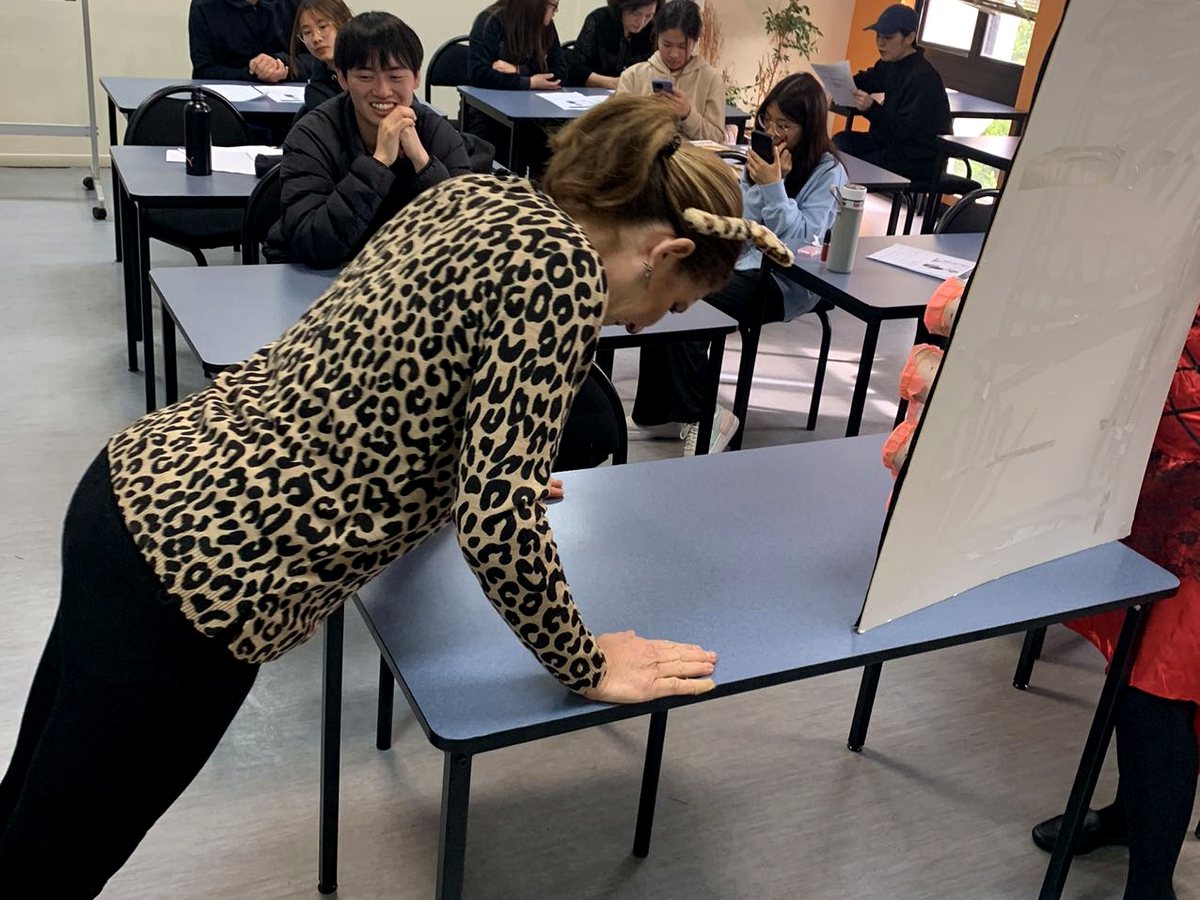 An interactive classroom scene at WIE showing a teacher in animal-print attire engaging with students...