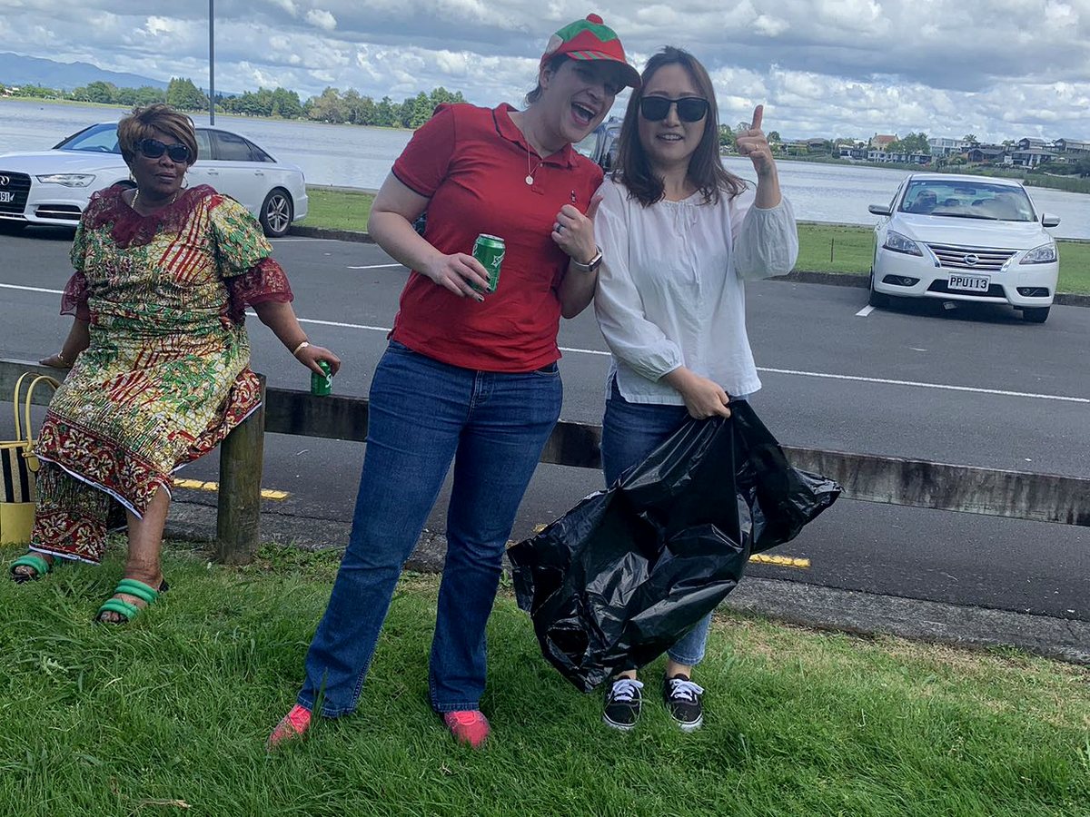 Three international women participating in an outdoor community activity at Hamilton Lake, smiling and...