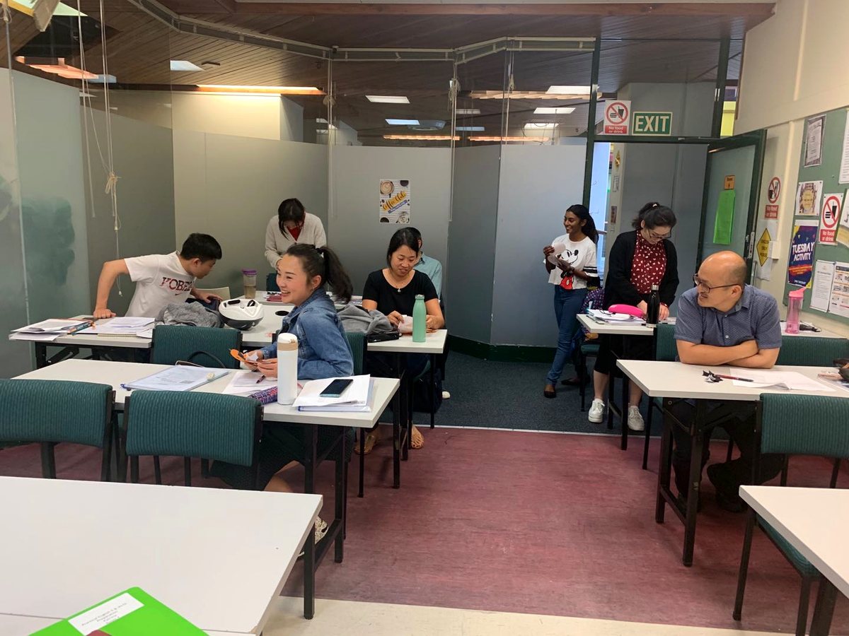 Diverse adult international students engaged in interactive classroom study and group learning in an...