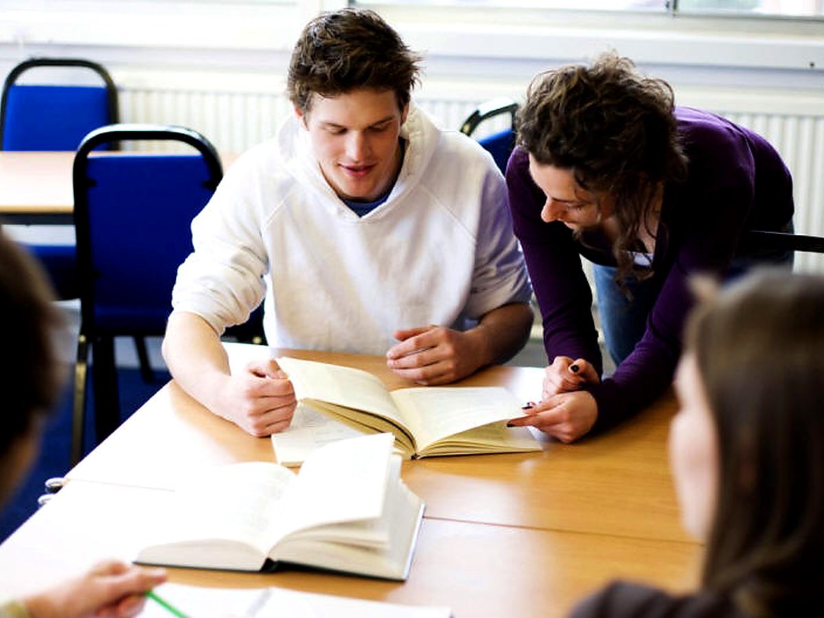 A teacher supports a student during classroom learning.