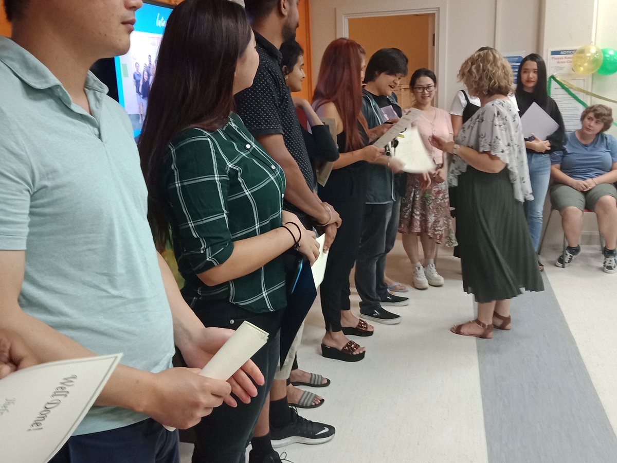 Students line up indoors at Waikato Institute of Education to receive completion certificates from a staff...